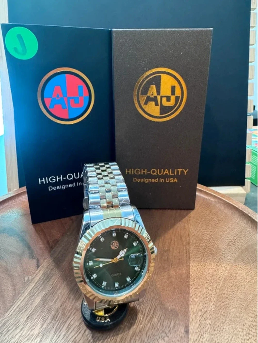 AJ stainless steel watch, green face, gold & silver toned band